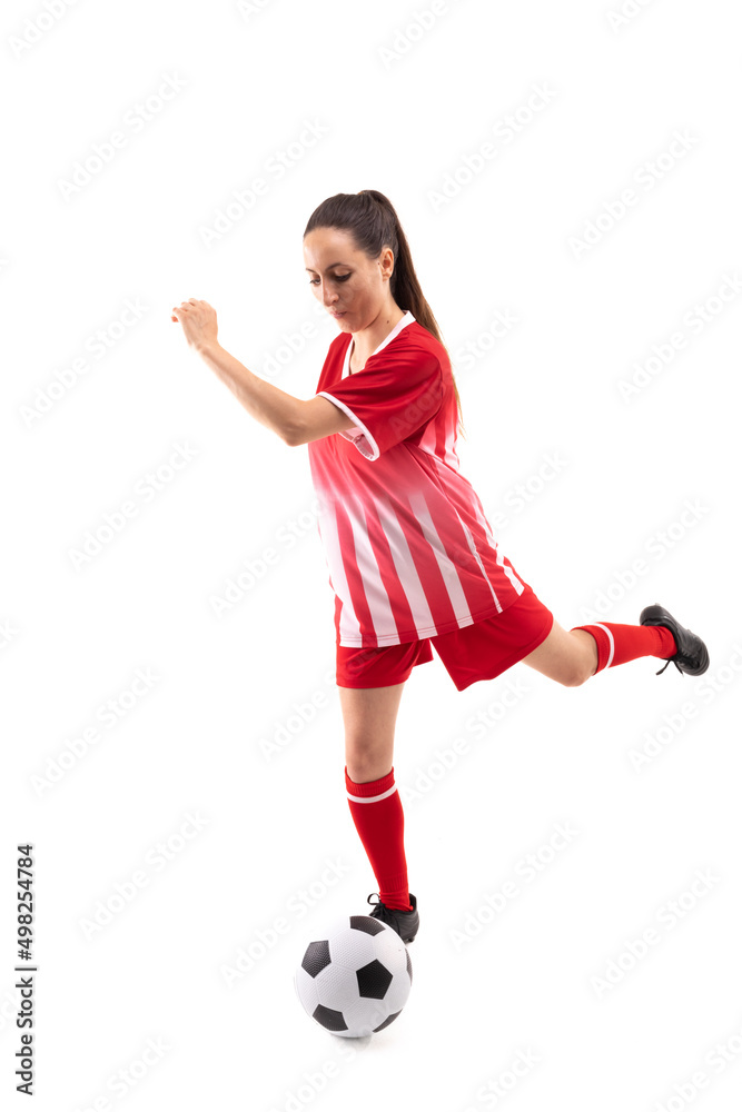 Caucasian young female player kicking soccer ball while playing soccer against white background