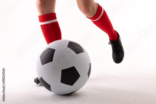 Low section of caucasian young female soccer player playing soccer against white background