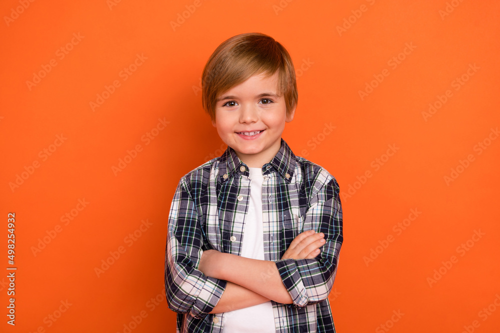 Photo of young cheerful little boy crossed hands wear casual clothes isolated over orange color background Photo of young cheerful little boy crossed hands wear casual clothes isolated over orange color background