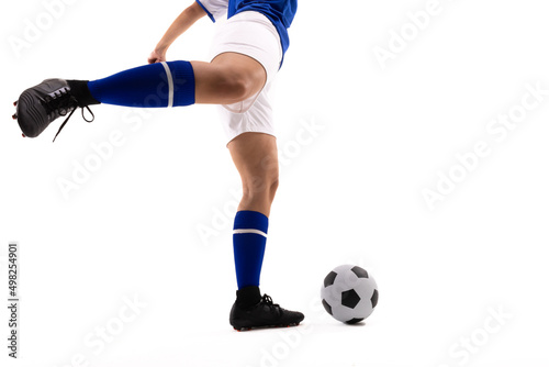 Low section of biracial female soccer player kicking soccer ball against white background