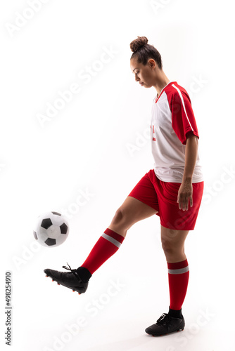 Full length of biracial young female soccer player juggling soccer ball with foot