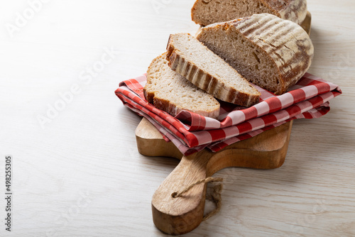 Close-up of sliced bread with checked pattern napkin on serving board with copy space