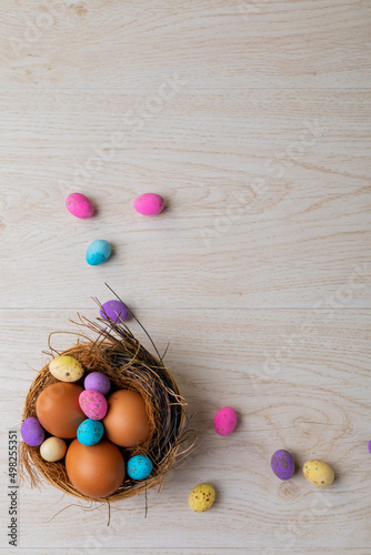 Overhead view of eggs and colorful candies in nest on table during easter