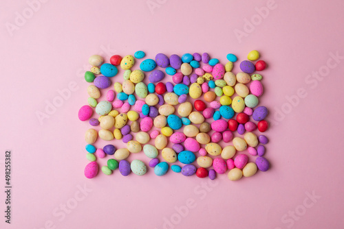 Directly above shot of colorful candy easter eggs arranged in rectangle on pink background