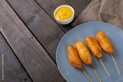 High angle view of corn dogs served in plate by mustered sauce in bowl on table
