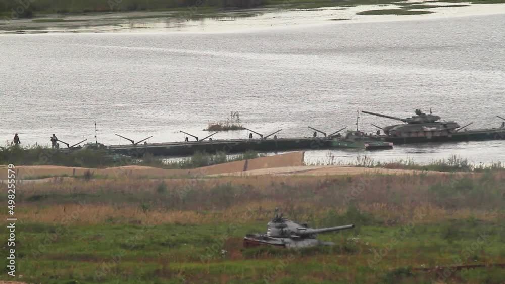 The passage of tanks on a pontoon bridge over a water obstacle of a military training ground. The passage of tanks on a pontoon bridge over a water obstacle of a military training ground.