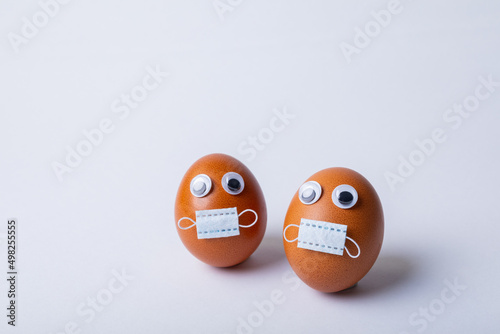 Close-up of doodle eyes and mask on easter eggs over white background