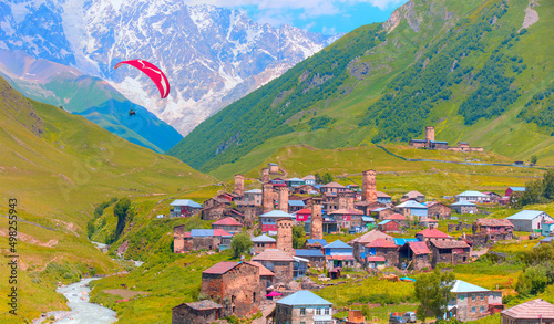 Paraglider flies in the sky - Traditional ancient Svan Towers and in Ushguli village - Upper Svaneti, Georgia