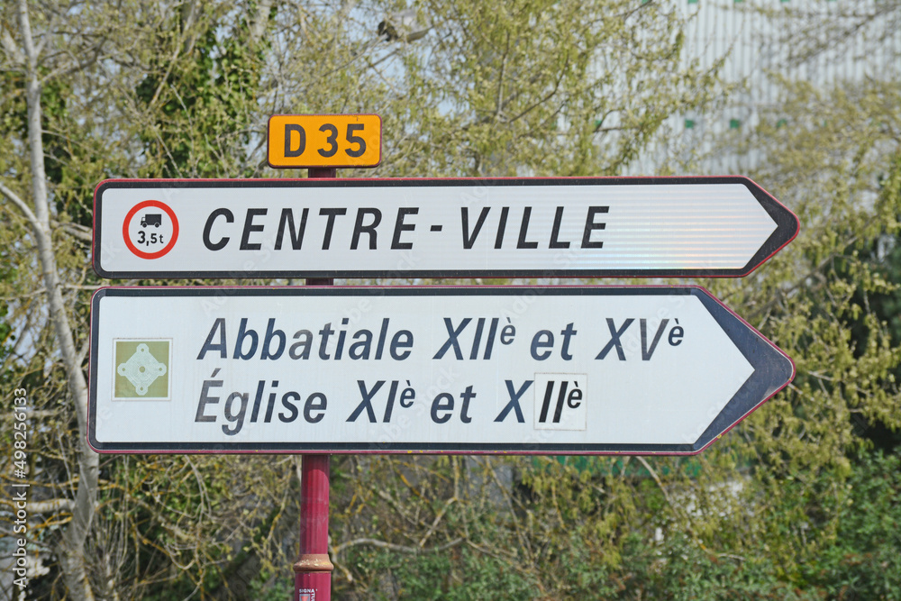 Panneau de signalisation : direction centre-ville, abbatiale et église.
