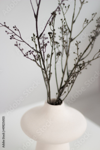 White vase on a white table with twigs.