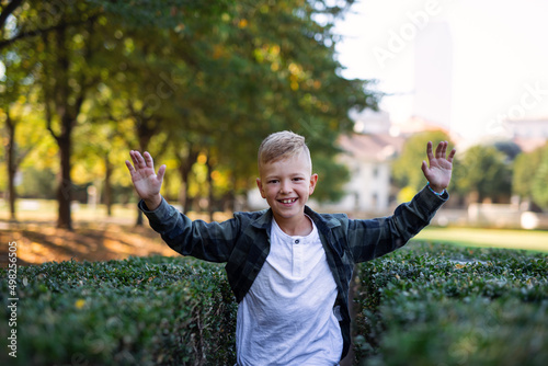 Happy little boy running and looking at camera outoodrs in park photo