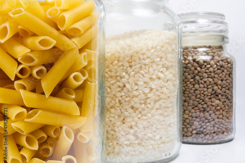 Pasta in a bag, macaroni, rice and lentils in glass jars on a white background