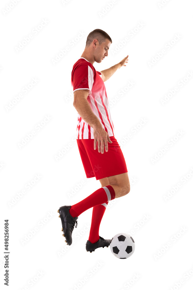 Young male caucasian athlete kicking soccer ball against white background