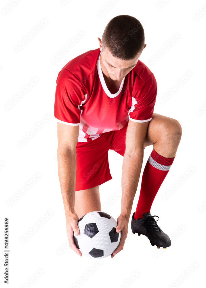 Full length of caucasian young male soccer player kneeling while holding ball over white background Full length of caucasian young male soccer player kneeling while holding ball over white background