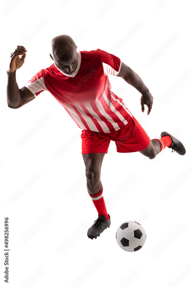 Full length of young male african american soccer player kicking ball on white background