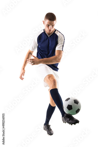 Confident young male caucasian player kicking ball against white background