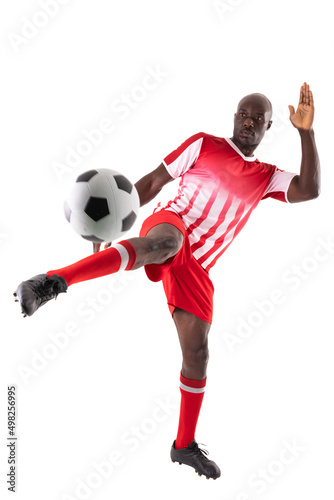 Fototapeta Naklejka Na Ścianę i Meble -  Confident young male african american soccer athlete kicking ball against white background