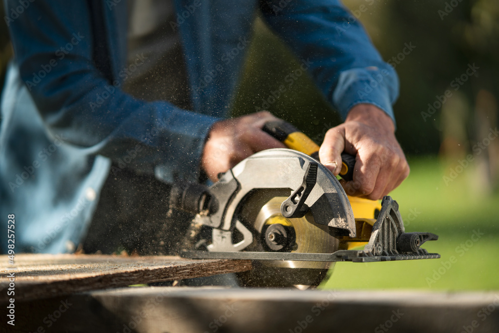 Close-up of craftsman working with circular saw at construction site Close-up of craftsman working with circular saw at construction site
