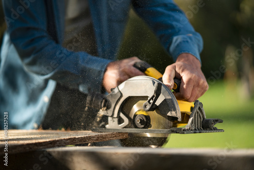Close-up of craftsman working with circular saw at construction site