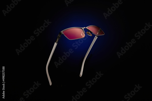 Sunglasses with pink lenses on a black-blue background.