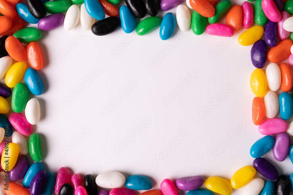 Directly above view of copy space amidst multi colored candies over white background