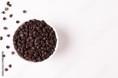 Overhead view of bowl full of chocolate chips by copy space on white background photo