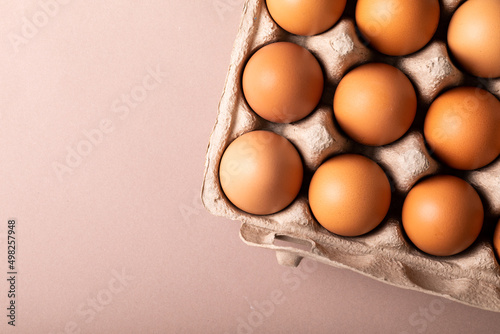 Directly above view of fresh brown eggs in carton by copy space over colored background