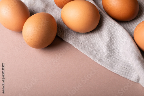 Close-up high angle view of fresh brown eggs and gray napkin over colored background with copy space