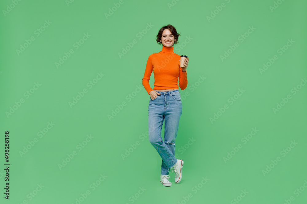 Full body young smiling happy woman 20s wear casual orange turtleneck hold takeaway delivery craft paper brown cup coffee to go isolated on plain pastel light green color background studio portrait Full body young smiling happy woman 20s wear casual orange turtleneck hold takeaway delivery craft paper brown cup coffee to go isolated on plain pastel light green color background studio portrait