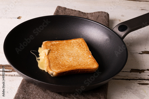 High angle view of fresh cheese sandwich in cooking pan on napkin over white table