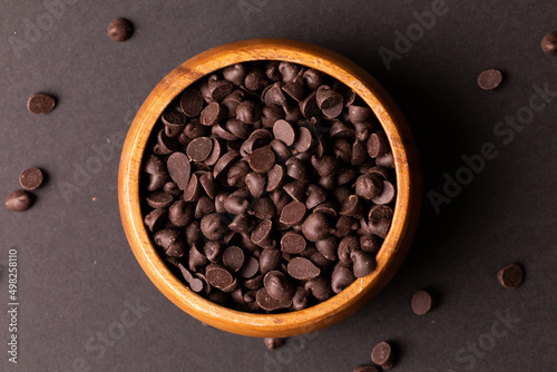 Directly above view of fresh chocolate chips in wooden bowl over colored background