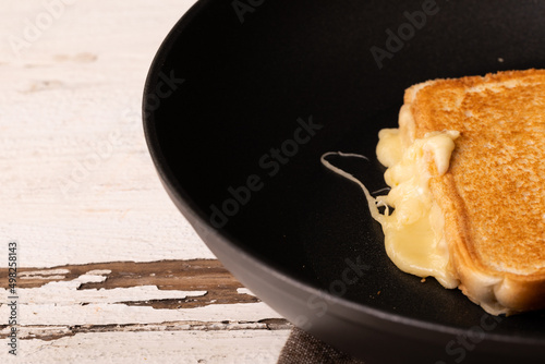High angle view of fresh melting cheese sandwich in cooking pan on white table