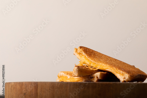 Close-up of cheese toast sandwich on wooden serving board against white background with copy space