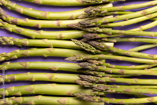 Full frame shot of raw green asparagus vegetables against purple background
