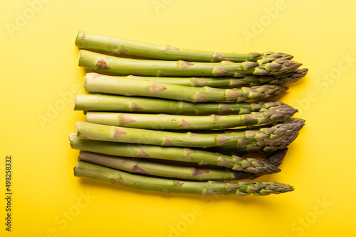 Overhead view of green raw asparagus vegetables against yellow background