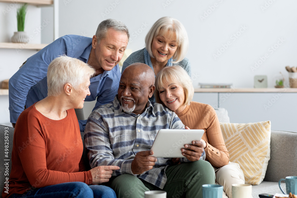 Cheerful elderly people spending time together at home, using