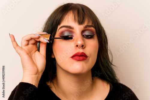 Young makeup artist woman holding a mascara isolated on white background