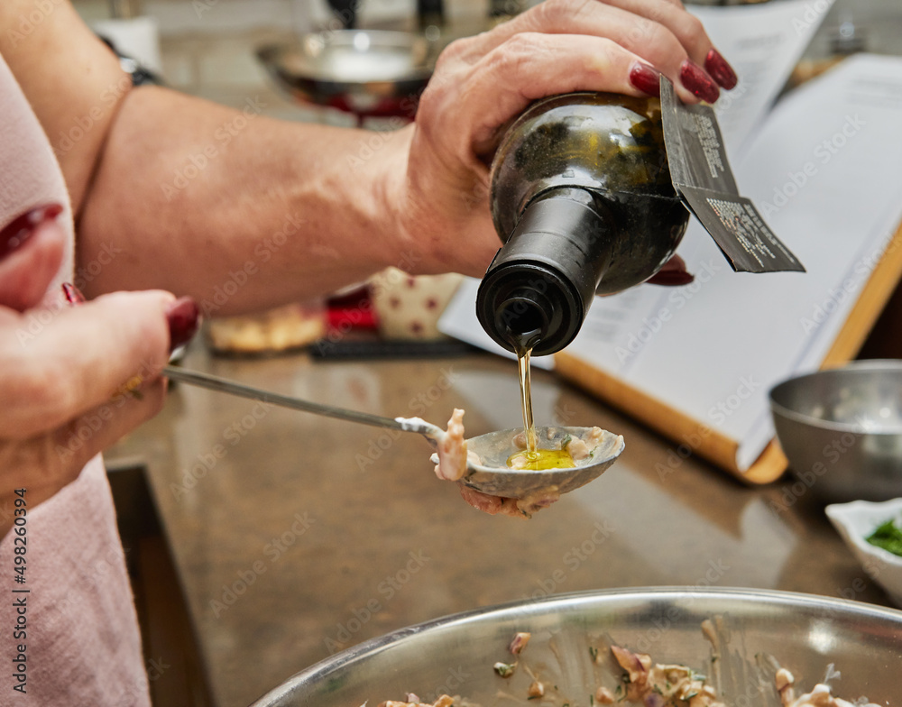 Chef pours olive oil from bottle into dish of salmon Chef pours olive oil from bottle into dish of salmon