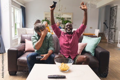 Multiracial senior male friends enjoying video game at home