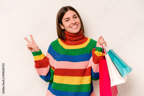 Young caucasian woman going to shopping isolated on white background joyful and carefree showing a peace symbol with fingers.