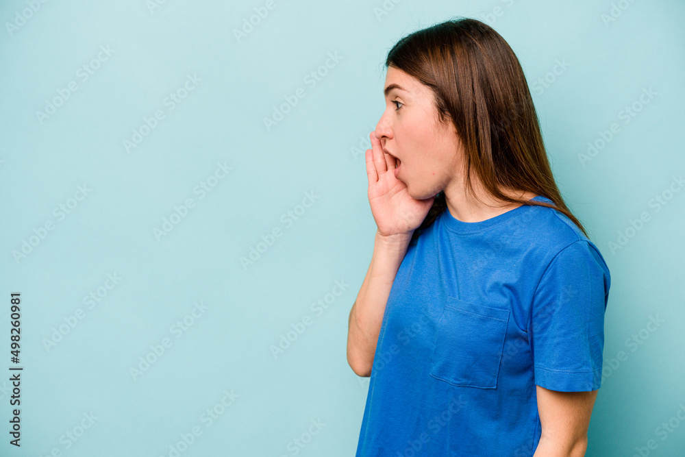 Young caucasian woman isolated on blue background is saying a secret hot braking news and looking aside Young caucasian woman isolated on blue background is saying a secret hot braking news and looking aside