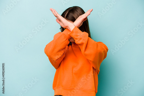 Quadro su tela Young caucasian woman isolated on blue background keeping two arms crossed, denial concept