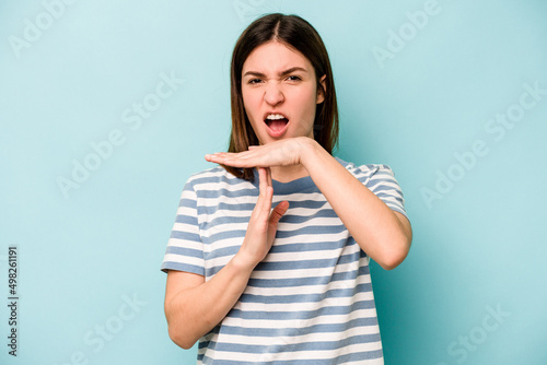 Young caucasian woman isolated on blue background showing a timeout gesture.