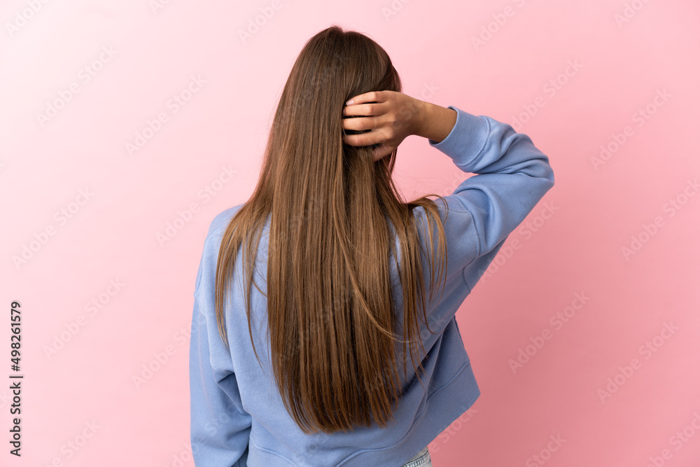 Young woman over isolated pink background in back position and thinking Young woman over isolated pink background in back position and thinking