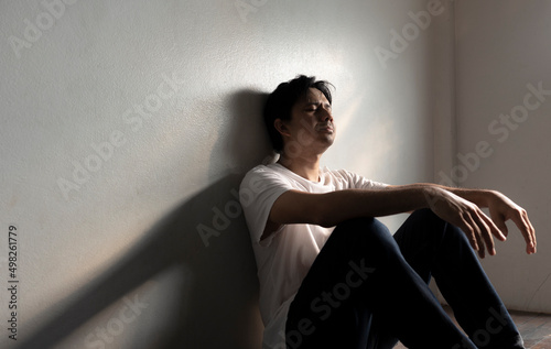 Asian man leans against a wall with stress, depression, and despair, man has life problems