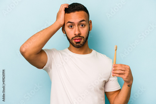 Young hispanic man brushing teeth isolated on blue background being shocked, she has remembered important meeting.
