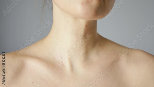 Woman with touching her skin in collarbone area with brown mole and nevus, strokes her fingers along clavicles. photo