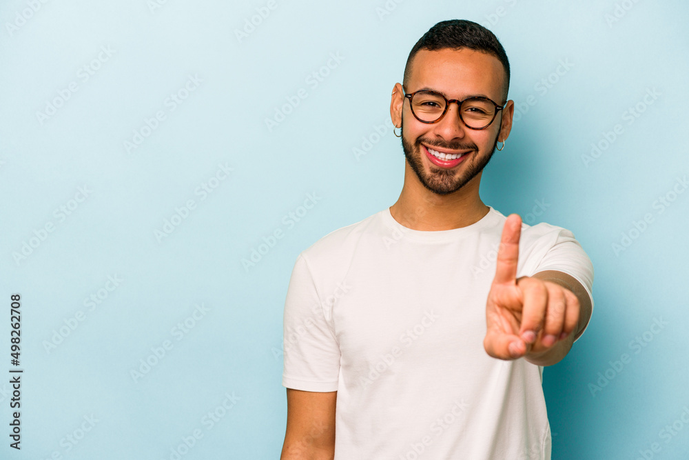 Young hispanic man isolated on blue background showing number one with finger. Young hispanic man isolated on blue background showing number one with finger.