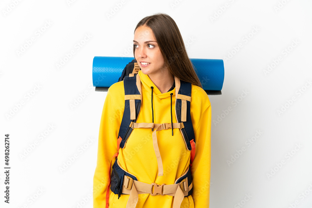Young mountaineer woman with a big backpack over isolated white background looking side Young mountaineer woman with a big backpack over isolated white background looking side
