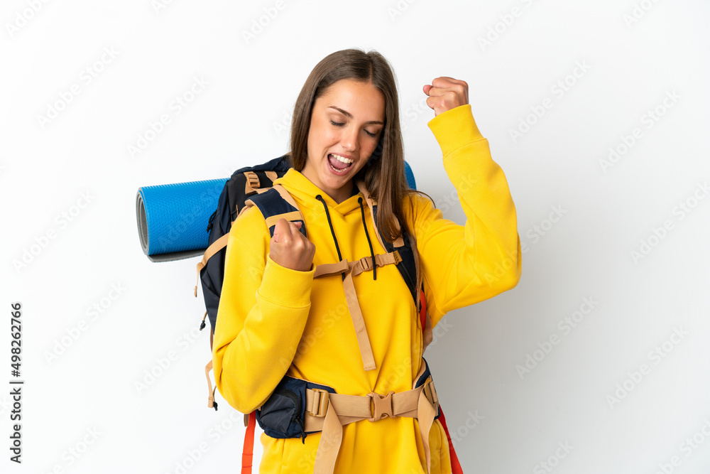Young mountaineer woman with a big backpack over isolated white background celebrating a victory Young mountaineer woman with a big backpack over isolated white background celebrating a victory